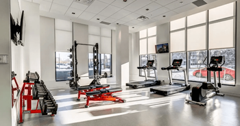 A gym with a variety of equipment including treadmills, weights, and exercise machines.